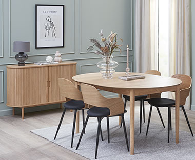 Sala da pranzo moderna composta da un tavolo in legno circondato da quattro sedie e una credenza chic di legno