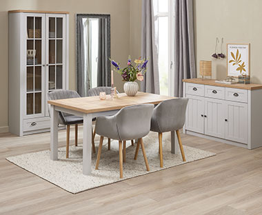 Sala da pranzo con mobili di colori chiari comprendenti una vetrina e una credenza bianchi e un tavolo e quattros sedie in tessuto grigio