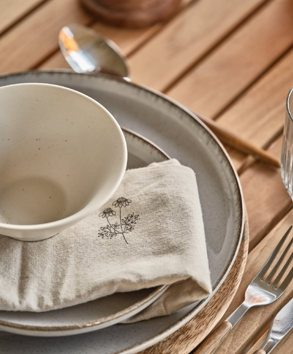 Assiette et bol en porcelaine, nappe aux couleurs naturelles et fourchettes