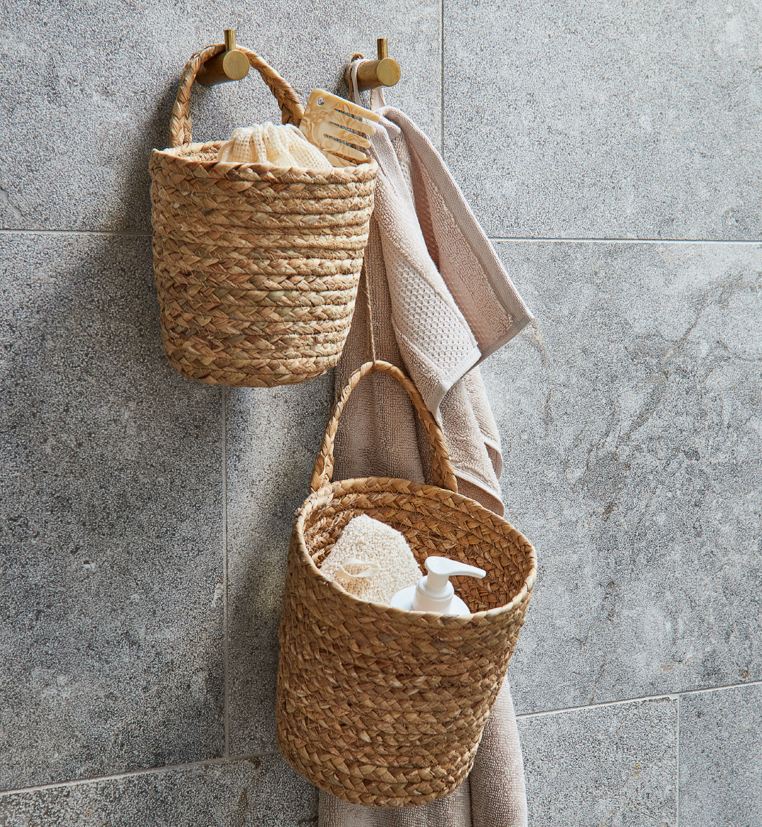 Cesti pensili decorativi appesi su parete da bagno accanto asciugamano beige