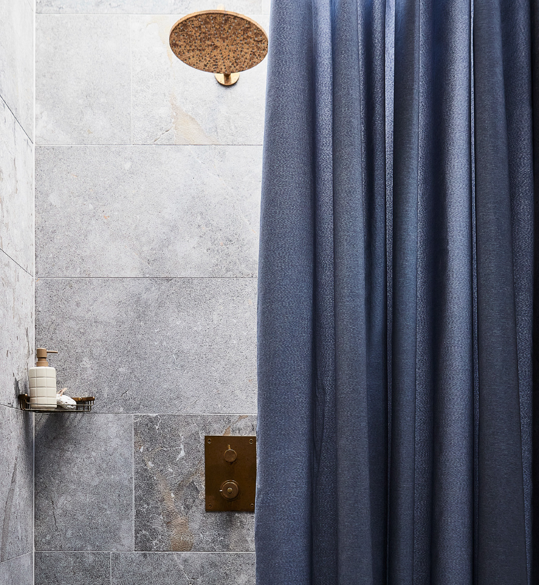 Douche avec carreaux de pierre et rideau bleu